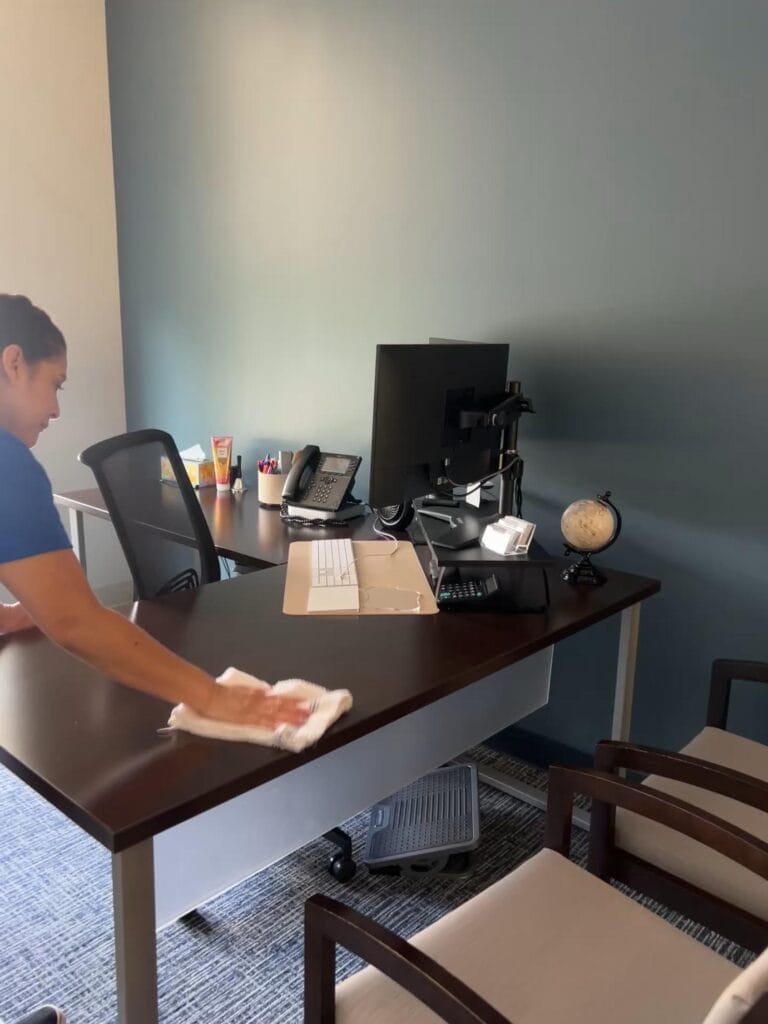 A cleaner from CK Cleaning wipes down a desk in one of their service areas.